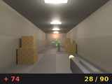 A first-person view down a warehouse corridor with crates and a gun.